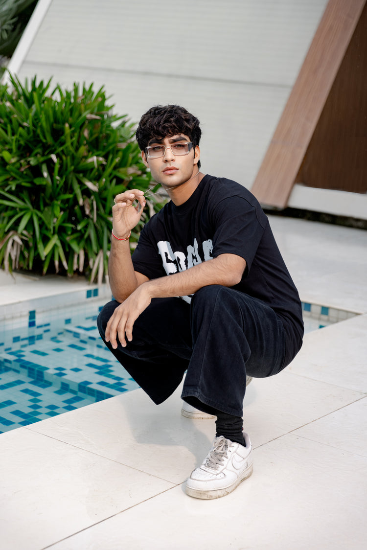 Man in black outfit squatting by a pool