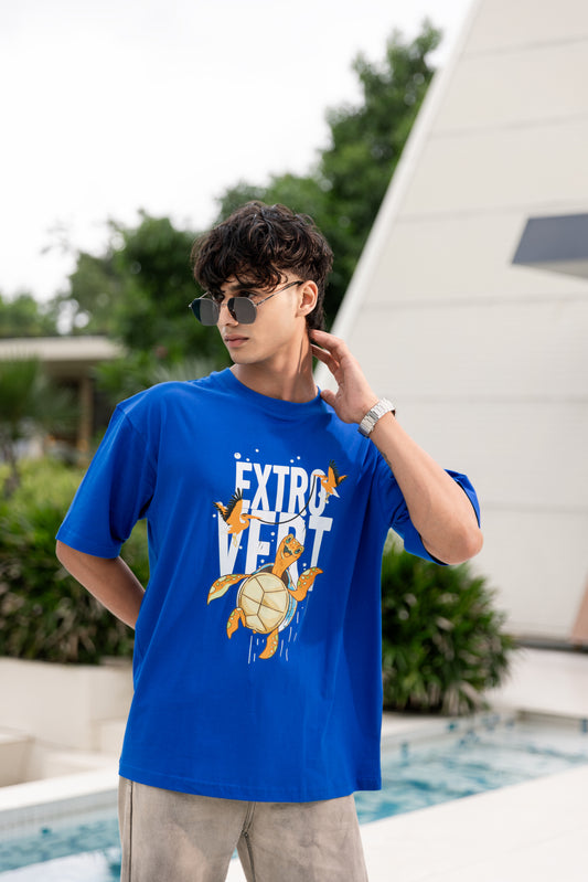 Person wearing a blue t-shirt with a graphic design outdoors by a pool