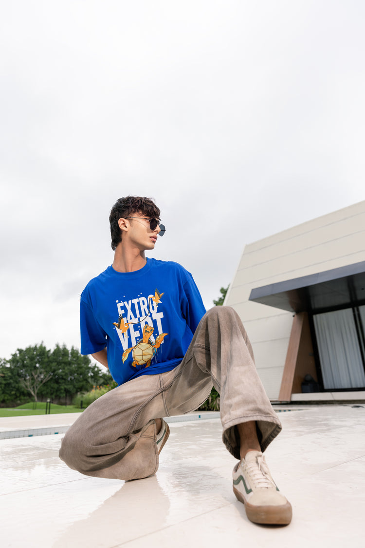 Person wearing a blue t-shirt with text and graphics, sitting outdoors.