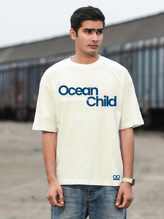 A man wearing an oversized white t-shirt with the text 'Ocean Child'.