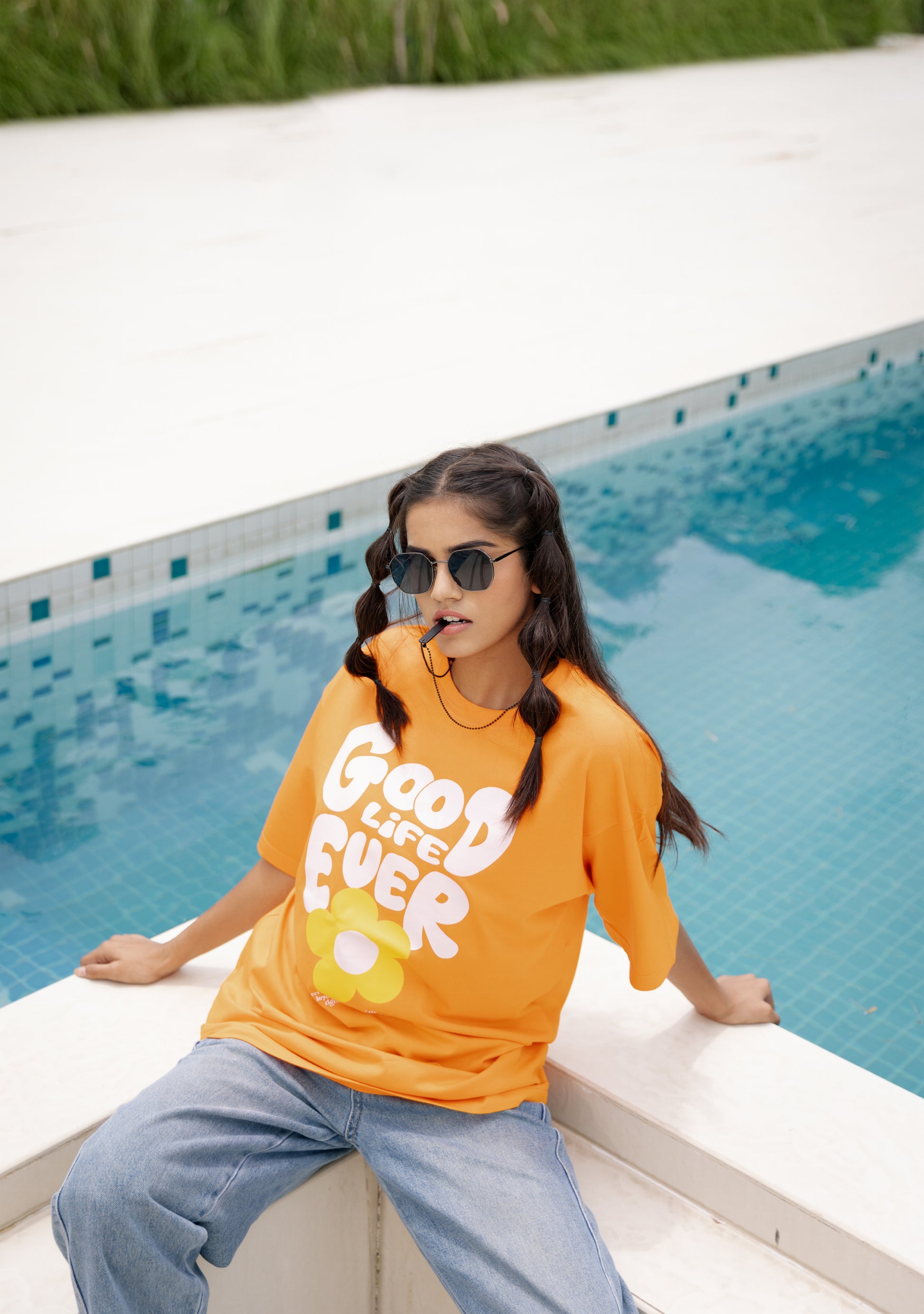 Person wearing an orange shirt with text by a pool
