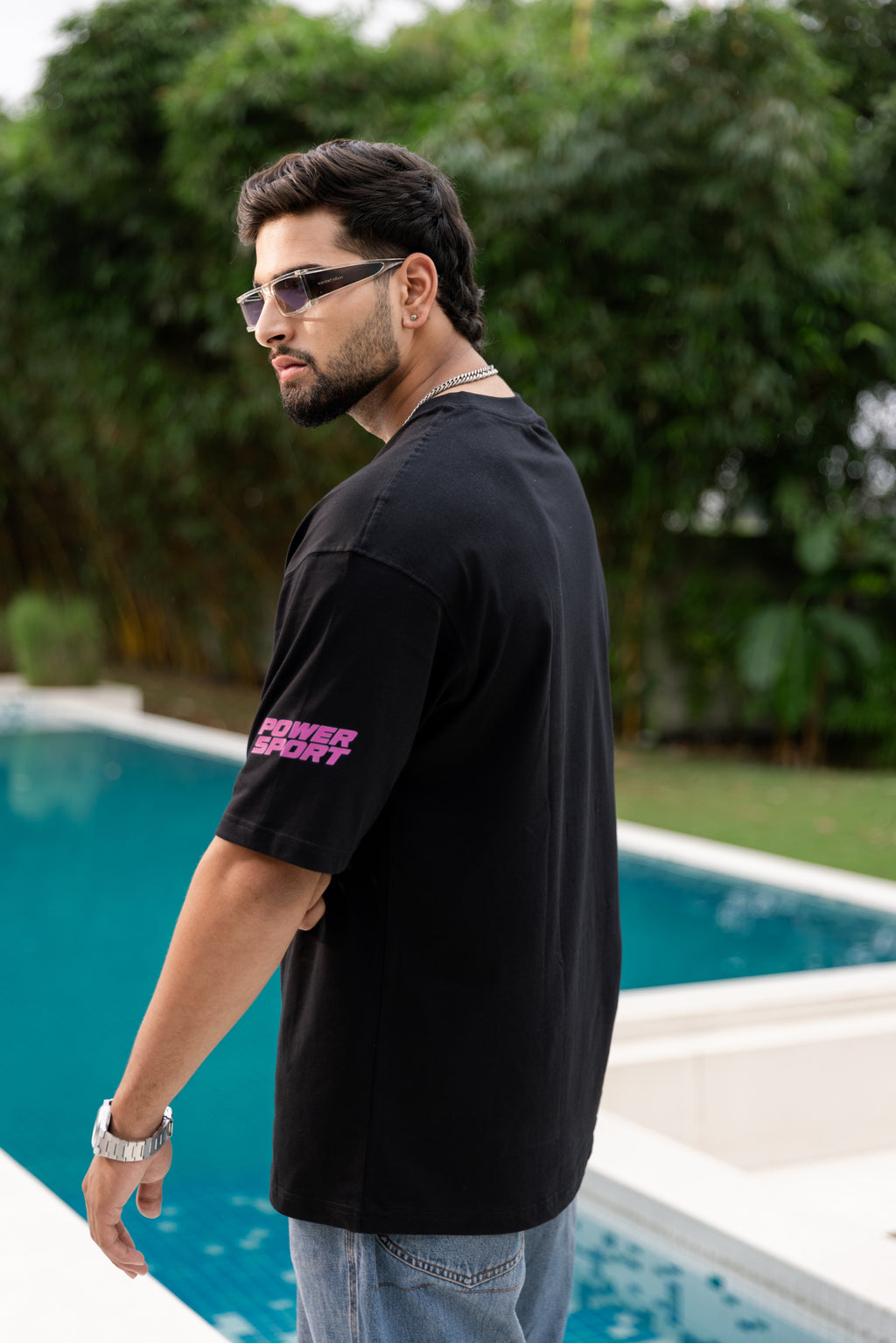 Man wearing a black t-shirt with pink text by a poolside