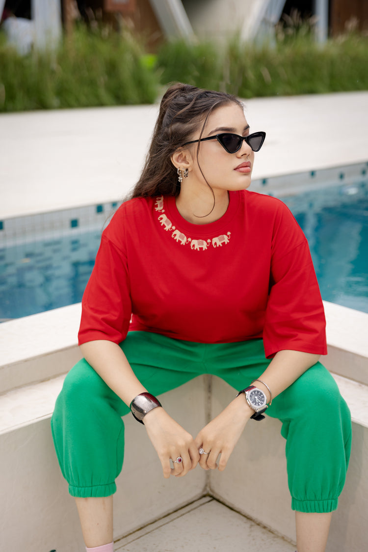 Woman in red top and green pants sitting by a pool