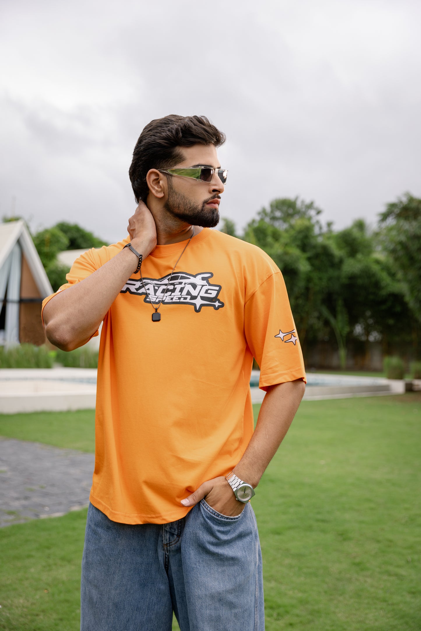 Man wearing an orange t-shirt with a logo, standing outdoors.