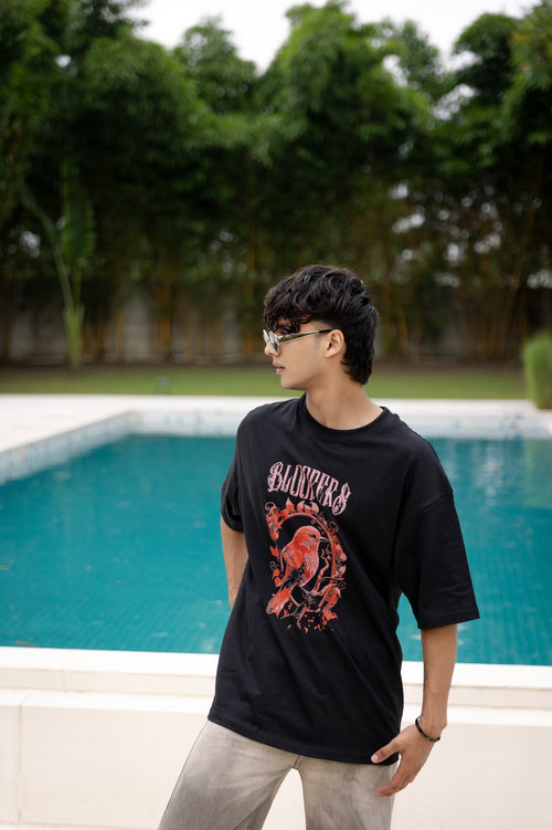 Person wearing a black t-shirt with a graphic design by a pool