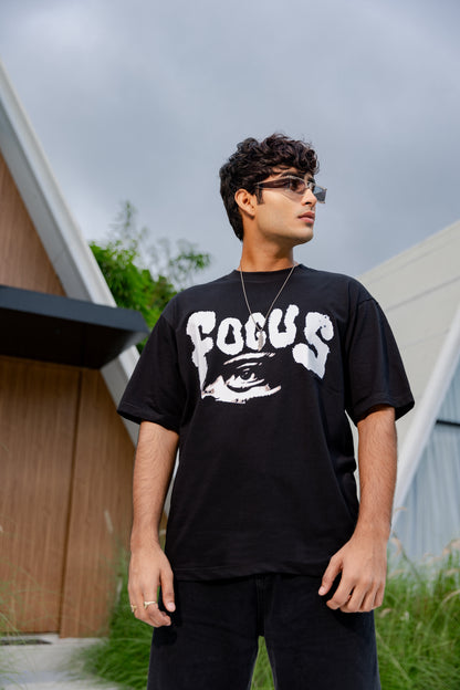 Man wearing a black 'FOCUS' t-shirt outdoors.