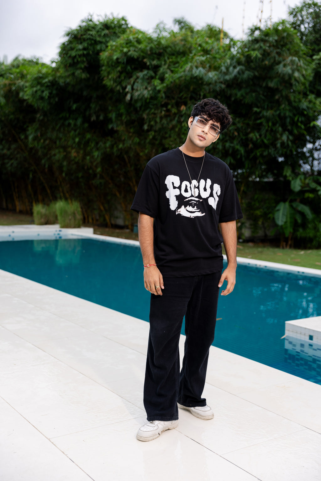 Person wearing a black t-shirt with 'FOCUS' text by a poolside