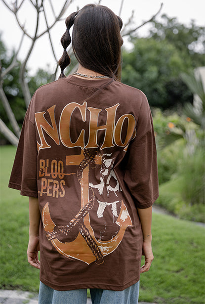 Girl wearing a brown t-shirt with 'INCHO BLOO' print outdoors