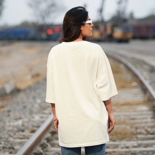 Person wearing a white oversized t-shirt standing on train tracks