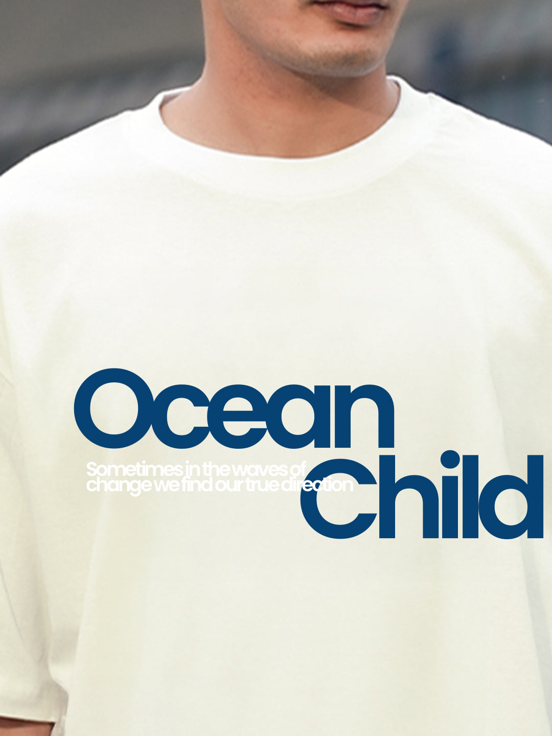 Person wearing a white t-shirt with 'Ocean Child' text in blue.