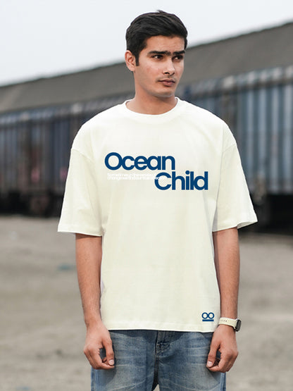 A man wearing an oversized white t-shirt with the text 'Ocean Child'.