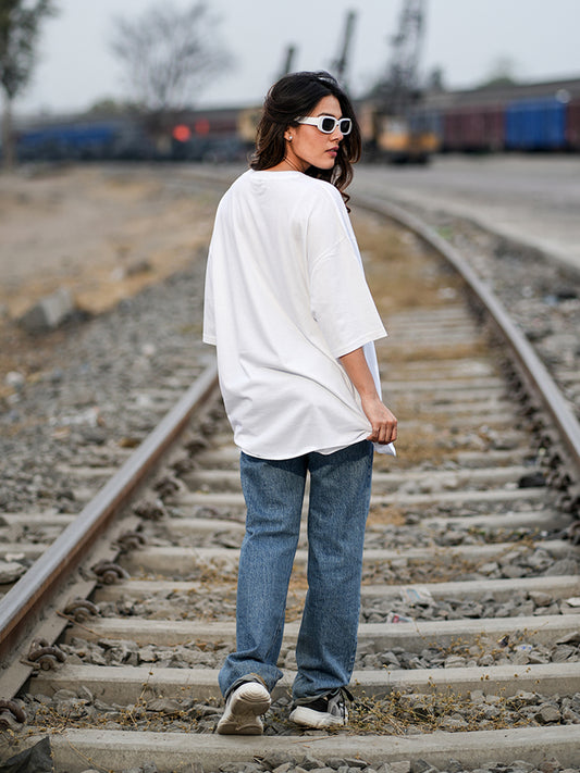 Person wearing a white oversized t-shirt and blue jeans 