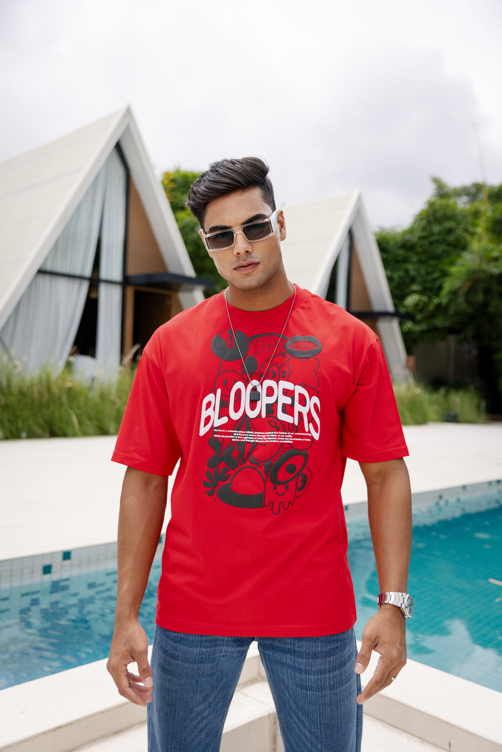 Man wearing a red 'Bloopers' t-shirt by a pool 