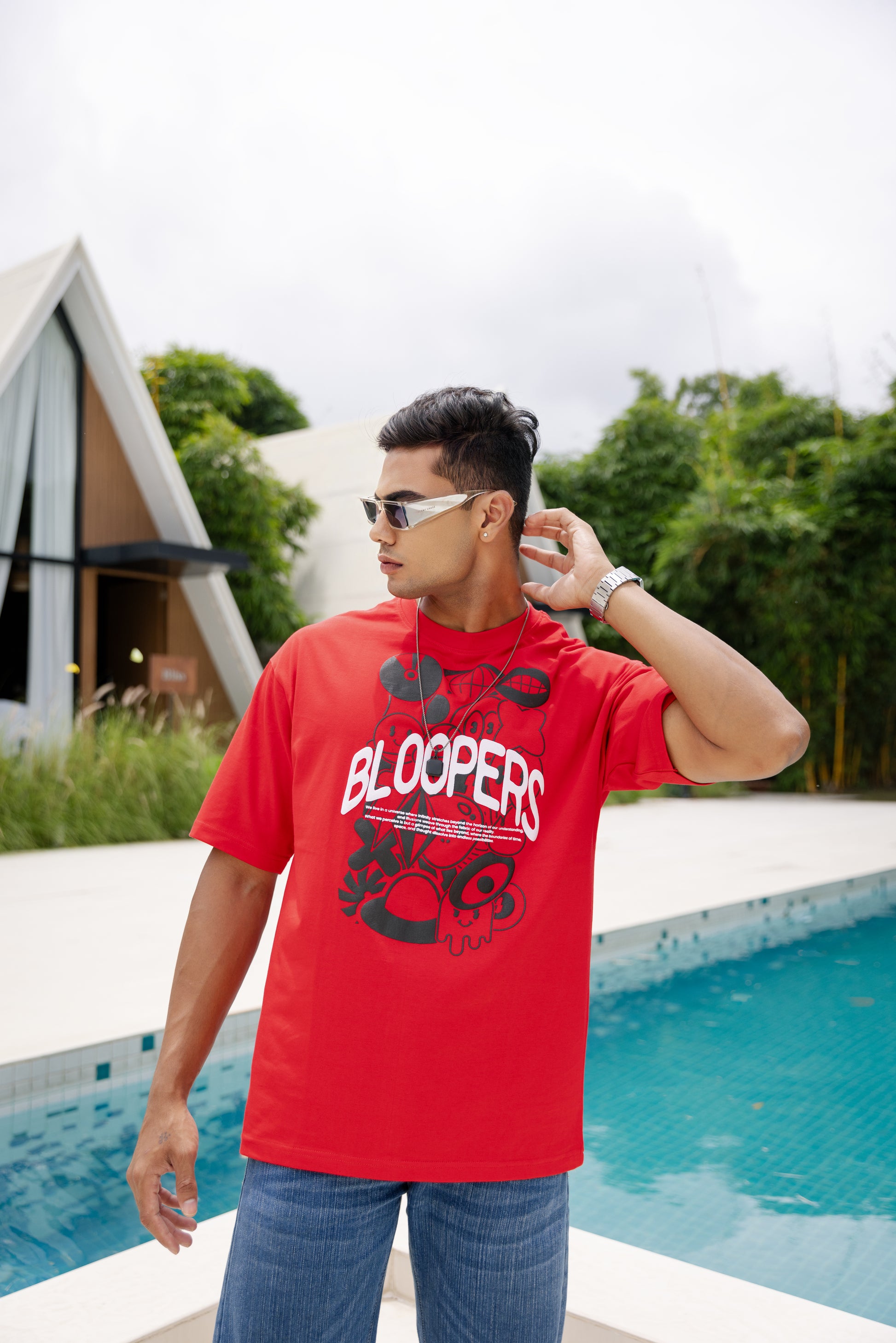 Man wearing a red t-shirt with 'Blooppers' text by a poolside