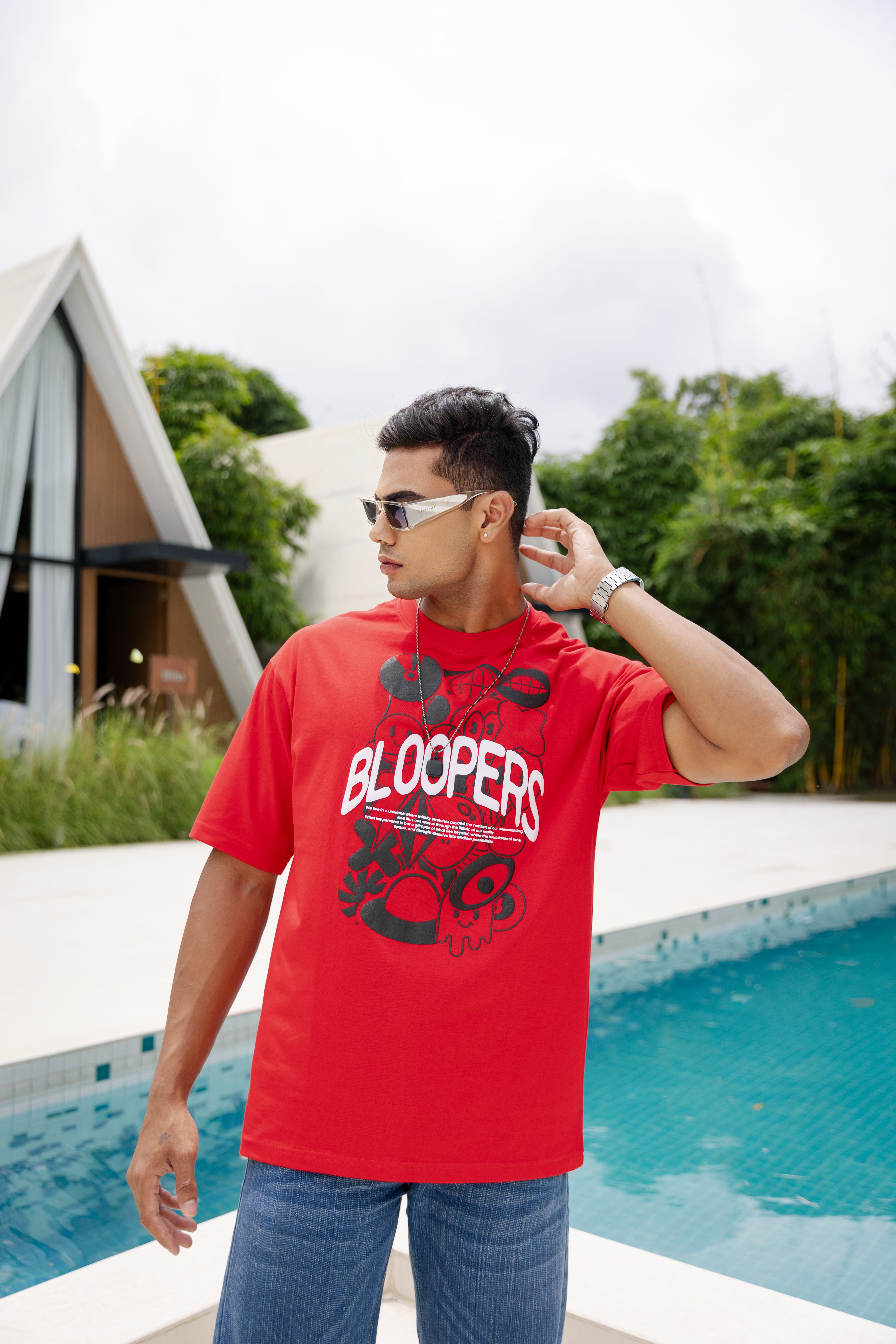 Man wearing a red t-shirt with 'Blooppers' text by a poolside