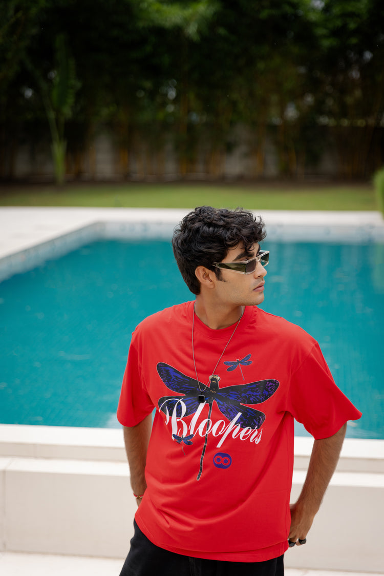 Man wearing a red t-shirt with a butterfly design by a pool